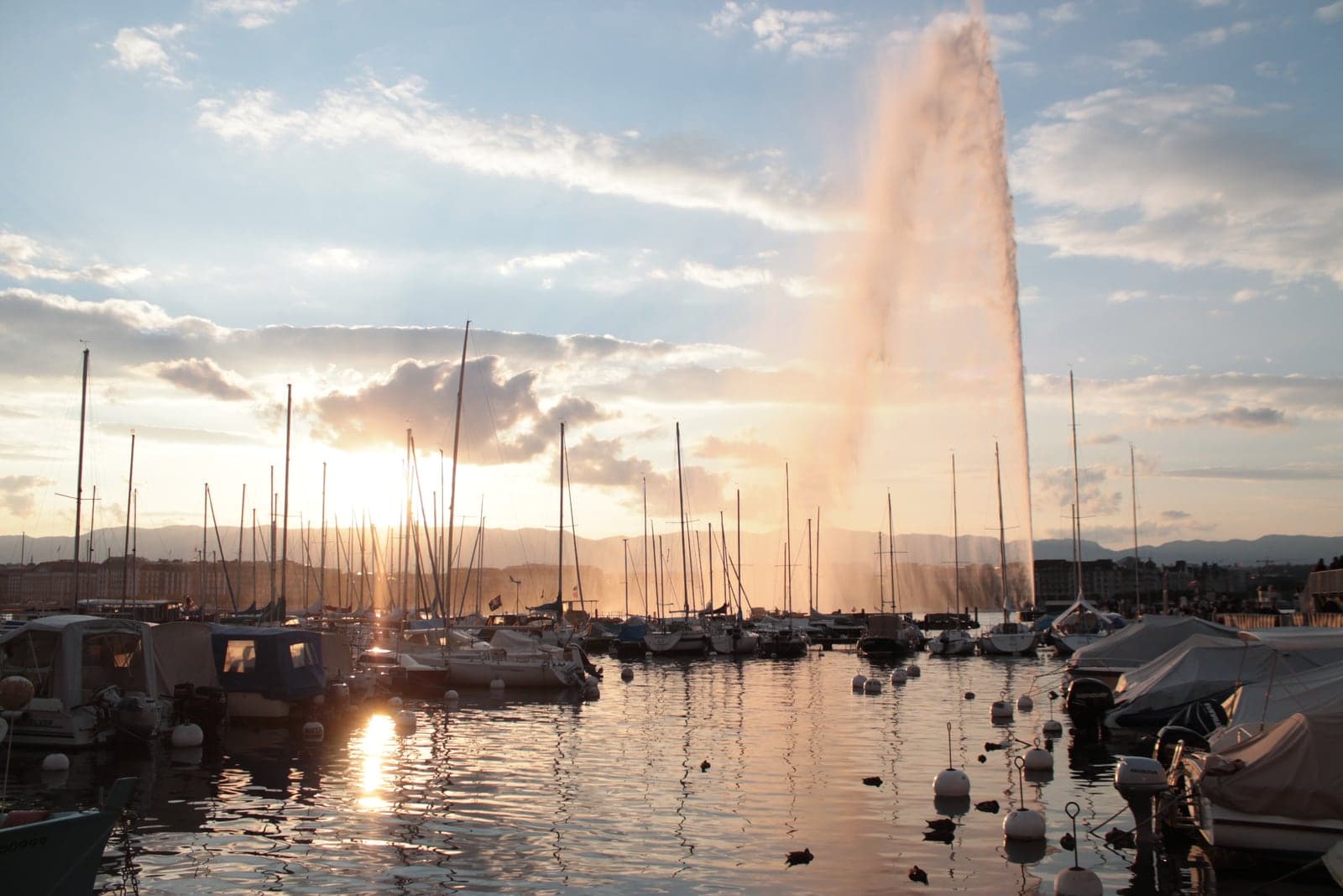 Warm evening light on the Jet d'Eau and sailboats in Geneva's lakeside harbour